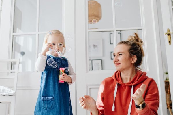 A joyful moment of a mother and daughter playing with bubbles indoors.